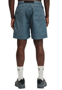 Blauwe shorts voor heren met een elastische tailleband, een achterzak en een horizontale streeptekstuur. Gecombineerd met grijze schoenen en crewlengte sokken.
