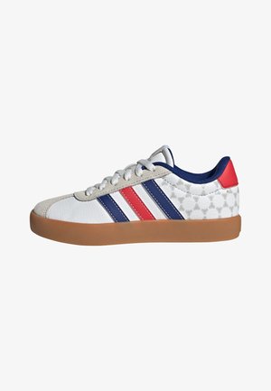 Biały sneaker z niebieskimi i czerwonymi paskami, gumową podeszwą, niebieską wyściółką, czerwoną pętelką na pięcie oraz szarą zamszową nasadką na palce, widoczny z boku.