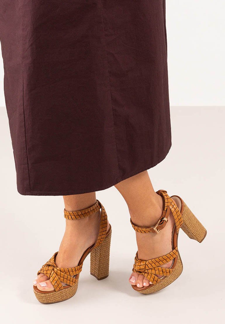 Sandalias de plataforma trenzadas en marrón con un grueso tacón cuadrado, que presentan un diseño trenzado y una correa en el tobillo con detalle de hebilla.