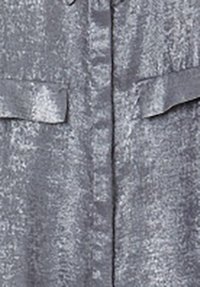Metallic silbernes Hemd mit strukturiertem Finish, ausgestattet mit zwei Brusttaschen und einer Knopfleiste. Weicher Stoff mit leichtem Glanz.