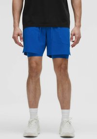 Blå atletiska shorts med sidofickor, elastisk midja och dragsko; tillsammans med vita sneakers och vita kalsongstrumpor.