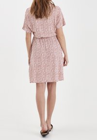 Šaty s krátkým rukávem s květinovým vzorem v odstínech růžové a bílé, s elastickým pasem a volným střihem do délky ke kolenům.