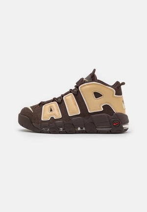 Basket montante marron et beige avec de grandes lettres « AIR » sur le côté et un amorti visible dans la semelle.