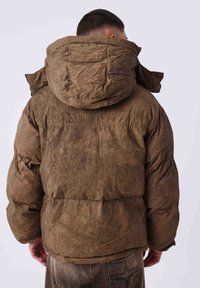 Chaqueta acolchada marrón con acabado texturizado y capucha extragrande. Cuenta con cintura entallada, puños elásticos y detalles de costuras mínimas.