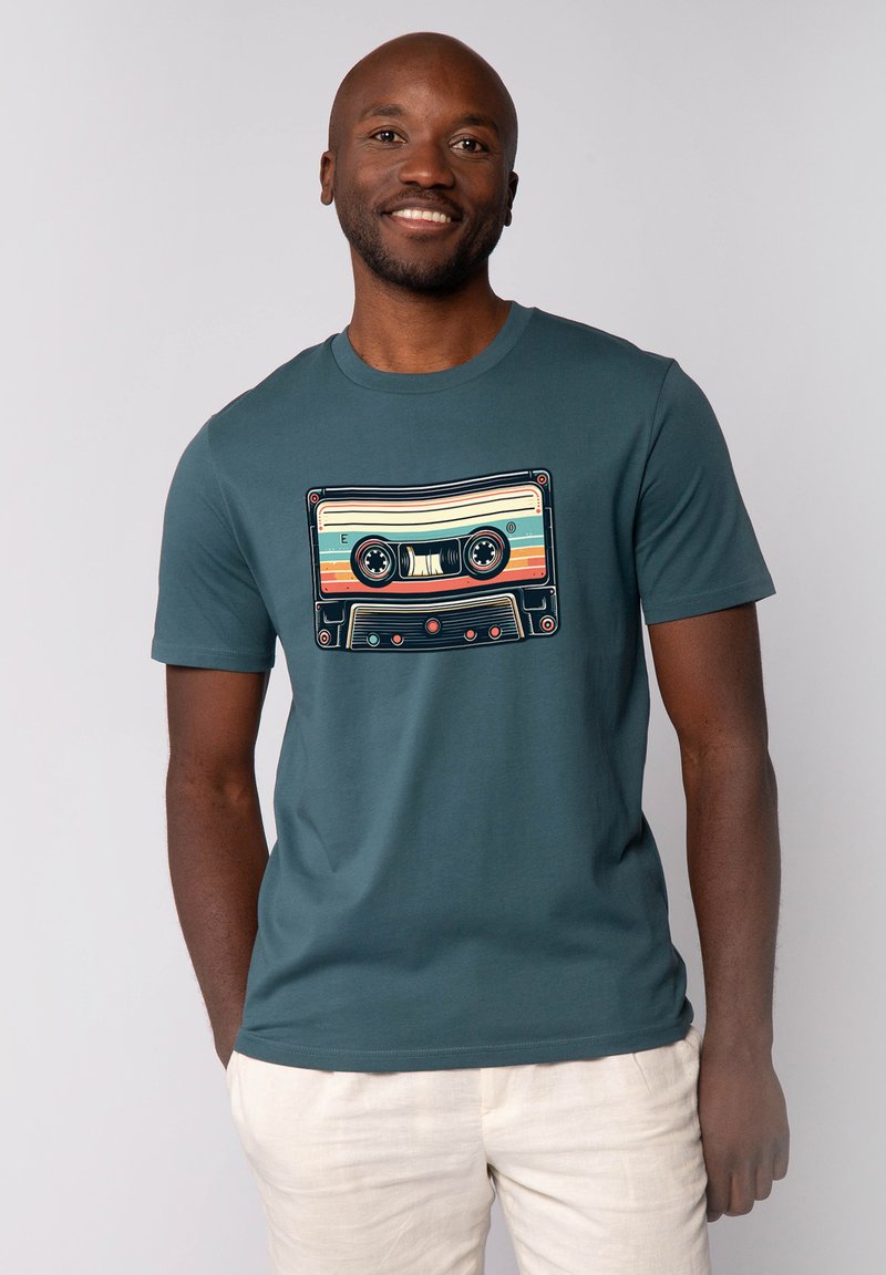 Teal T-shirt met korte mouwen, voorzien van een retro cassettebandje grafiek met kleurrijke strepen en zwarte details, gecentreerd op de borst.