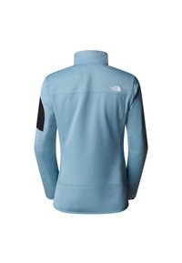 Vaaleansininen fleece-takki korkealla kauluksella, mustilla kyynärpäälapuilla ja logolla takan yläosassa. Sileä pinta ja istuva muotoilu.