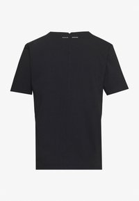 Svart bomull T-shirt med korta ärmar, rund halsringning och en central sömdetalj på baksidan. Har logotext nära halsen.