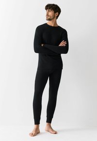Black long-sleeve shirt and matching leggings made of a soft, ribbed fabric. The fitted design features cuffed sleeves and ankles.