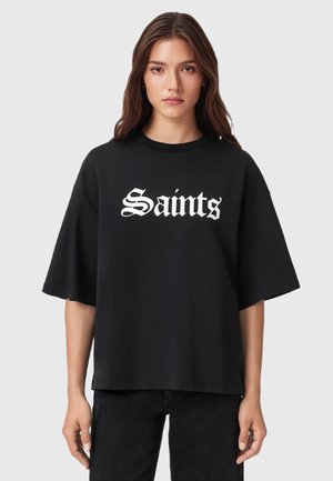 T-shirt nera oversize realizzata in morbido cotone misto, con una scritta bianca in grassetto "Saints" in un font stilizzato sulla parte anteriore.