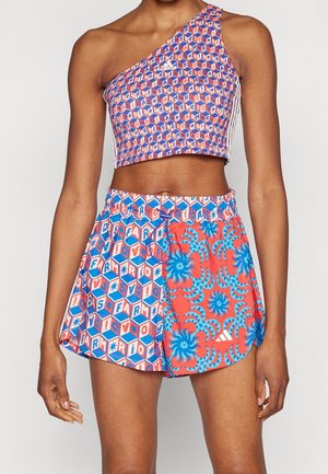 Farbenfrohes Sportoutfit mit einem einseitigen Crop-Top mit sechseckigen Mustern und Shorts mit blauem Blumenmuster sowie elastischem Bund.