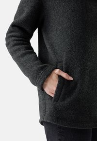 Pullover in pile di color grigio scuro con superficie testurizzata, dotato di tasca laterale e polsini a costine. Design semplice e dal taglio rilassato.
