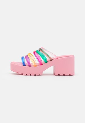 Roze platform sandalen hebben een stevige blokhak en transparante banden met veelkleurige accenten in rood, oranje, geel, groen, blauw en paars.