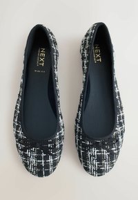Schwarz-weiße Tweed-Ballerinas mit einem weichen Innenfutter, runder Zehenpartie und dekorativem Schleifenakzent. Verfügt über ein breites Design für zusätzlichen Komfort.