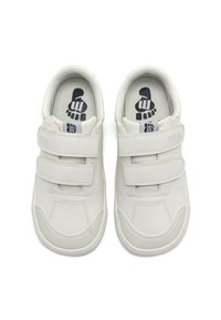 Baskets blanches avec des bandes Velcro, revêtement en cuir synthétique lisse, bout rond, col rembourré et semelle en caoutchouc texturée. Graphique de pied noir à l'intérieur.