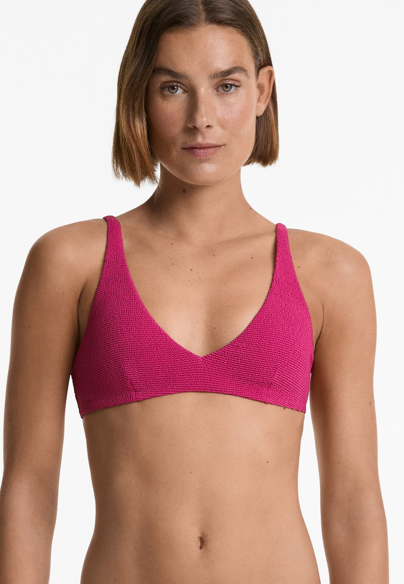 Růžový pletený bralet s hlubokým V- výstřihem a tenkými ramínky. Texturovaný materiál má po celé ploše konzistentní vzor.