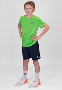 Groene short-sleeve shirt, marineblauwe shorts en witte sokken. Sneakers hebben grijze en oranje accenten. Eenvoudig ontwerp, lichtgewicht stof.