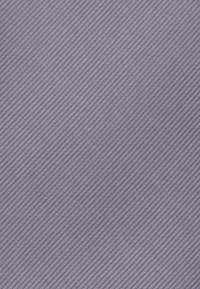 Tessuto lavanda con una texture a righe diagonali, caratterizzato da linee sottili in un motivo coerente, che crea un aspetto superficiale liscio.