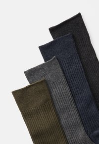 Vier paren geribbelde sokken in donkergroen, grijs, marineblauw en zwart. Gemaakt van een zachte, gestructureerde stof met een subtiele rek.