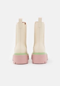 Białe botki za kostkę z gładkiej skóry. Posiadają różową podeszwę na platformie z zielonym akcentem. Dwa uchwyty z tyłu dla łatwego zakładania.