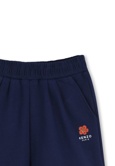 Granatowe spodnie dresowe z elastycznym pasem i boczną kieszenią ozdobioną małym czerwonym kwiatem oraz logo "KENZO PARIS" po prawej stronie.