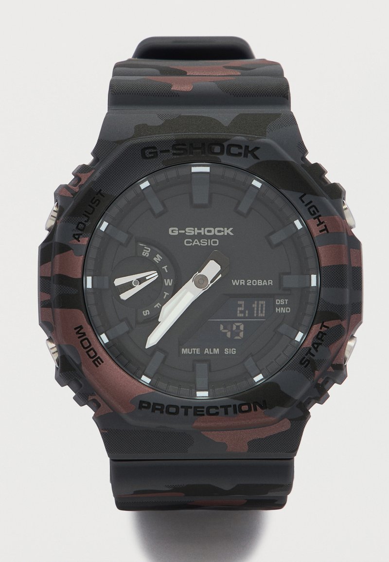 Μαύρο και καφέ πανομοιότυπο ρολόι Casio G-Shock με αναλογικούς δείκτες, μικρό πίνακα ημέρας της εβδομάδας και ψηφιακή εμφάνιση ημερομηνίας.