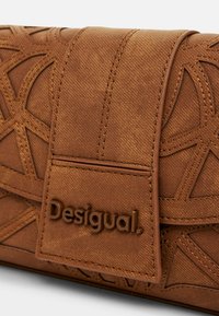 Brązowa torebka kopertowa o fakturze z wytłoczonym geometrycznym wzorem, z charakterystycznym logo Desigual w kontrastującym materiale.