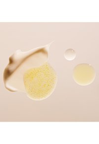 Tre klumpar av hudvårdsprodukter: en krämig off-white konsistens, en gul exfolierande gel med små korn och två klara vätskebubblor.