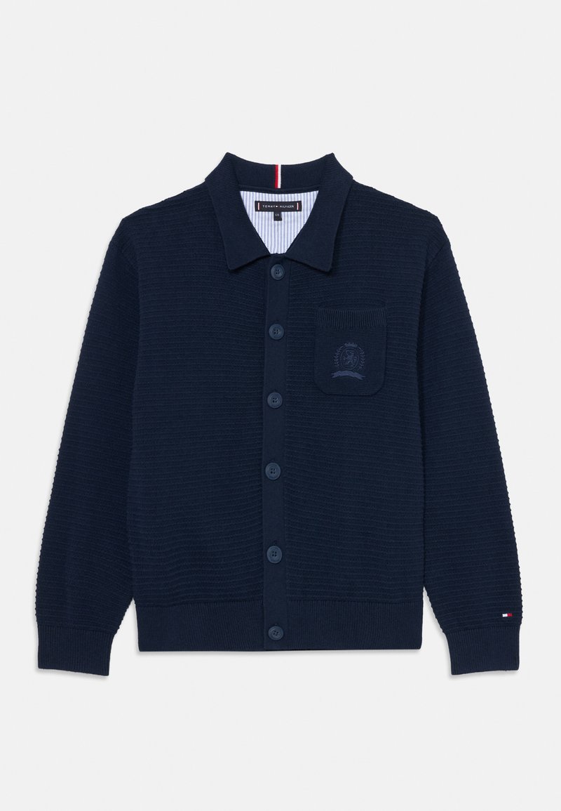 Tengerészeti kötött kardigán, galléros kivitelben, gombos elejű, bordázott textúrával és hímzett logóval ellátott mellzsebbel.