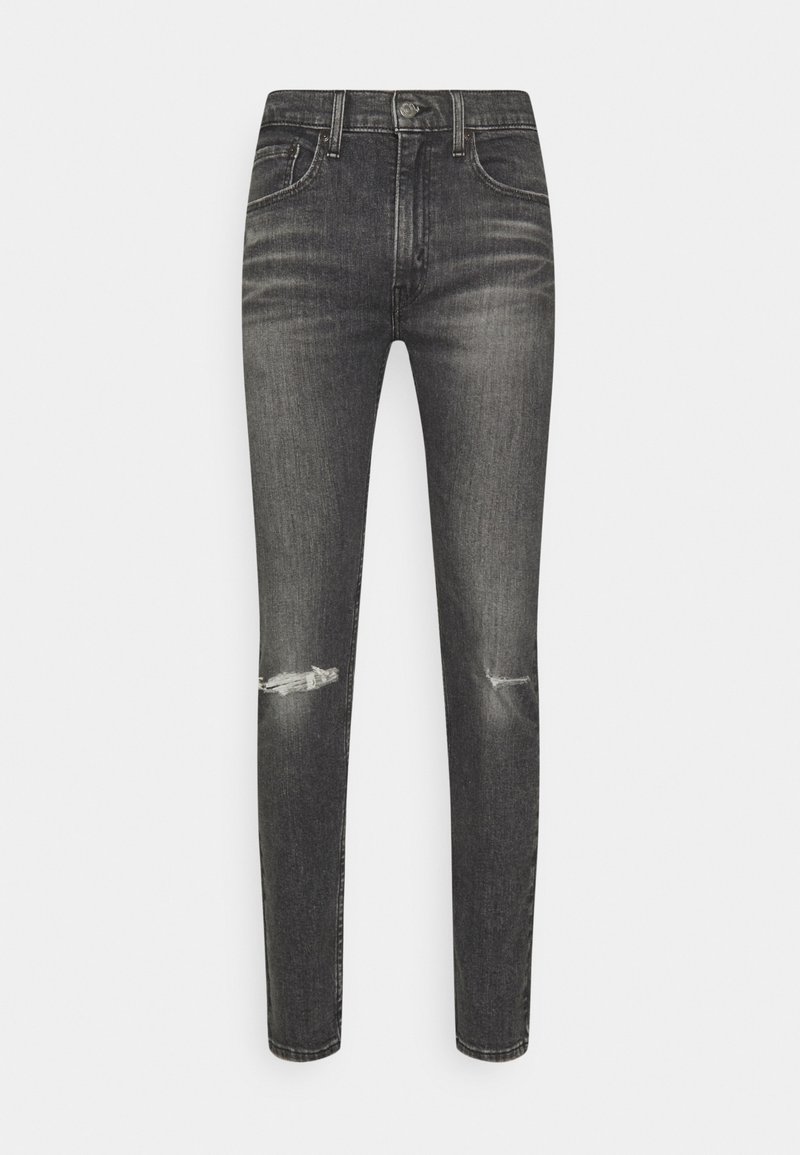 Černé skinny džíny s vybledlým vzhledem, obsahující dvě přední kapsy, jednu zadní kapsu a opotřebované detaily na kolenou.