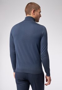 Navyblauer Rollkragenpullover aus geripptem Stoff, figurbetonter Schnitt, lange Ärmel, mit glatter Textur und subtilen Saumdetails.