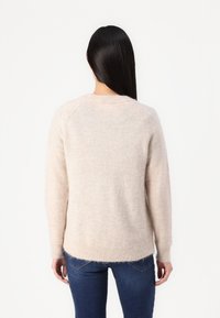 Hellbeige gestrickter Pullover mit langen Ärmeln, rundem Ausschnitt und geripptem Saum. Weiche Textur, leicht lockere Passform und nahtloses Schulterdesign.
