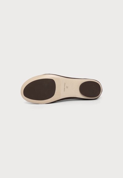 Semelle d'une chaussure beige avec des patins de préhension marron foncé au talon et aux orteils, étiquetée "Made in Italy", taille 37, sur un fond clair uni.