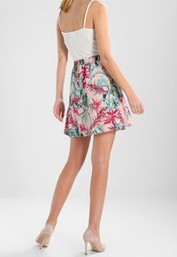 Jupe fleurie rose, présentant un imprimé vibrant avec des accents verts et violets. Fabriquée en tissu léger, avec une ceinture élastique pour plus de confort.