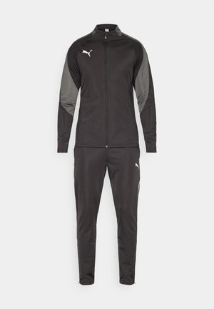 Black athletic tracksuit made of smooth fabric. Jacket has a full zipper and gray panels; pants have tapered legs and side pockets.