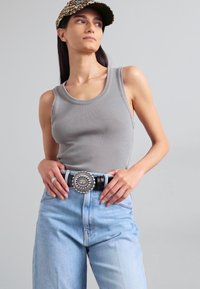 Gray ribbed tank top paired with light blue high-waisted jeans and a decorative black belt featuring a circular silver buckle.