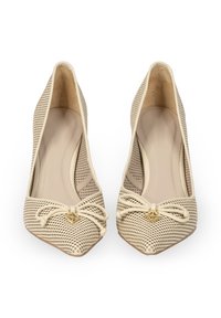 Beżowe, ażurowe szpilki z ostrym noskiem, z detalem w kształcie kokardy i złotym akcentem z przodu. Gładkie, wewnętrzne wykończenie.