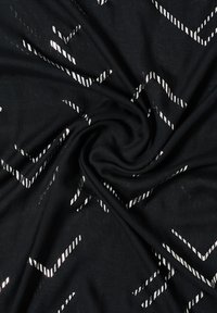 Tissu noir à texture lisse, ornée d'un motif géométrique blanc de bandes diagonales et de formes en chevrons.
