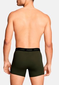Green boxer briefs with a black elastic waistband featuring the "PUMA" logo, smooth fabric, fitted design, shown from the back.