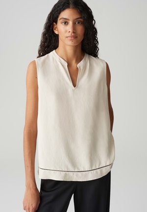 Mouwloze cremewitte blouse met een V-hals, voorzien van een subtiel patroon aan de onderkant, gemaakt van lichtgewicht stof, met een relaxte pasvorm en een gladde textuur.