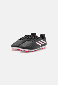 Botas de fútbol negras con una superficie texturizada, que presentan acentos rosas en la suela y los cordones, y tres franjas paralelas blancas en el costado.