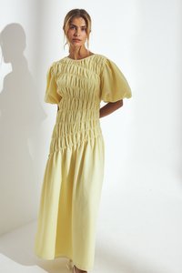 Robe jaune à manches bouffantes en tissu smocké texturé. Silhouette en A avec taille froncée et longueur sous le genou. Matériau léger et lisse.