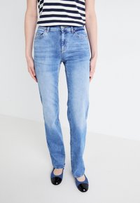 Vaqueros de mezclilla azul descolorido, de pierna recta y cintura media, con diseño de cinco bolsillos y sutiles detalles de desgaste en la parte frontal.