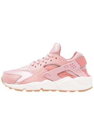 Pink athletic sneaker with textured and smooth panels, lace-up closure, white cushioned sole, and tan rubber outsole, side view.