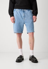 Shorts in denim azzurro chiaro con vita elastica, dotati di tasche laterali, dalla vestibilità rilassata e orlo justo sopra il ginocchio.