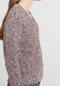 Mehrfarbiger Strickpullover mit V-Ausschnitt, strukturiertem Stoff mit einem gesprenkelten Muster, langen Ärmeln und einem lässigen Schnitt.
