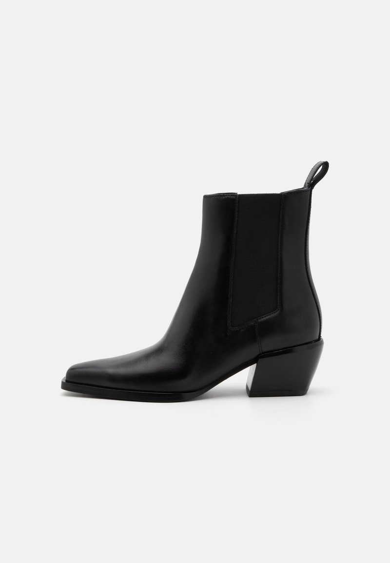 Bottine noire en cuir avec talon bloc incliné, panneau latéral élastique, bout pointu et languette à l'arrière.