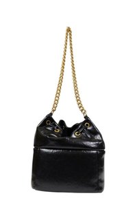 Borsa a secchiello in pelle nera con tracolla a catena dorata, dotata di chiusura con coulisse e dettagli dorati sulle aperture superiori. Texture liscia.