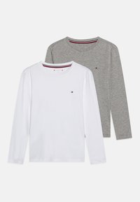 Två långärmade t-shirts med rund halsringning, en vit och en grå, var och en med en liten röd, vit och blå logotyp på vänster bröst.