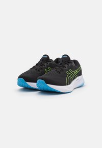 Scarpe sportive nere con upper in mesh, dettagli verde neon e suole in gomma blu. Presentano superfici texturizzate e una forma aerodinamica.
