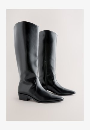 Botas negras de piel sintética hasta la rodilla con puntera puntiaguda y tacón grueso, con cremallera lateral y textura lisa. Diseño angular en la parte superior.